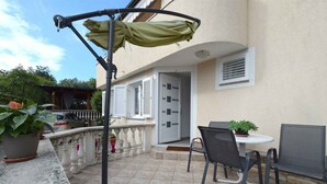 An outdoor patio with a table and chairs, a covered seating area, and a building entrance. - Holiday apartment mit Terrasse (Čižići)