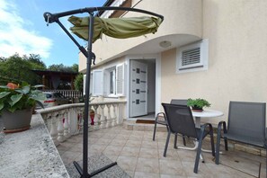 An outdoor patio with a table and chairs, a covered seating area, and a building entrance.