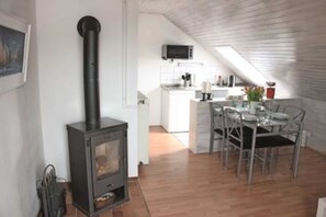 Une cuisine compacte comprenant une cuisinière, un coin repas avec une table et des chaises, et un petit îlot avec un évier.
