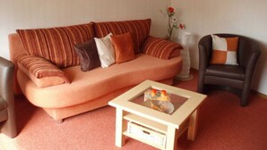 A living room with a sofa, a small table, and a chair. - Vacation apartment Haus am Sonnenhang - Holiday apartment (Bad Sachsa)
