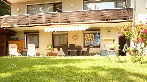 A two-story building with a balcony, outdoor seating area, and a small garden. - Vacation apartment Haus am Sonnenhang - Holiday apartment (Bad Sachsa)
