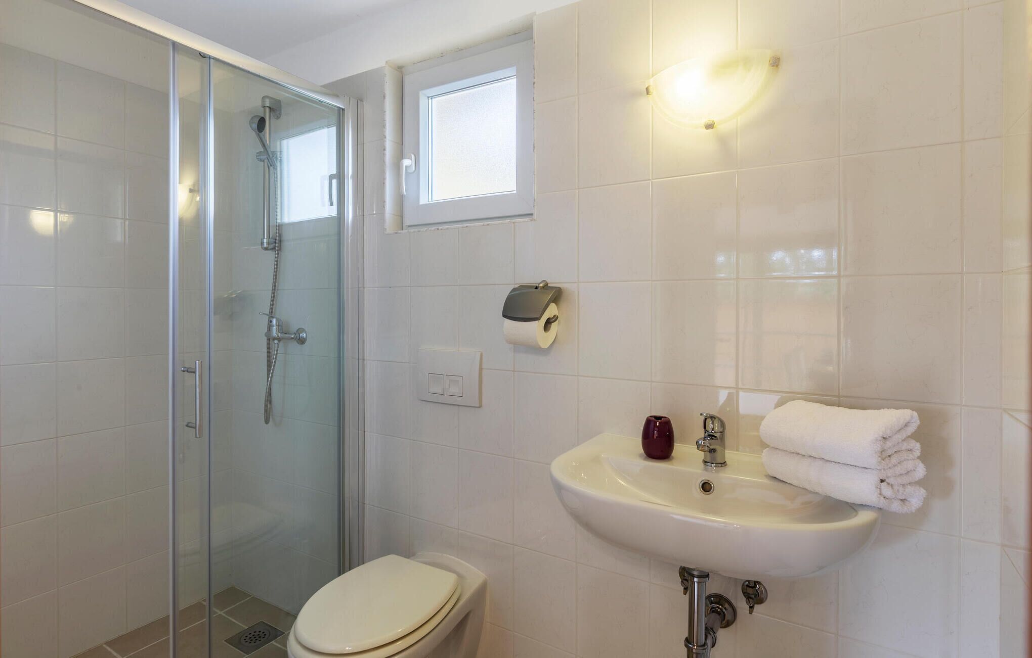 Une salle de bain avec une douche à parois de verre, des toilettes, un lavabo avec un porte-serviettes et un sèche-mains.