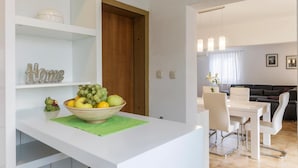A modern kitchen with a bowl of fruit on the counter, a 'Home' sign, and a dining area with a white table and chairs. - Amazing home in Labin (Labin)