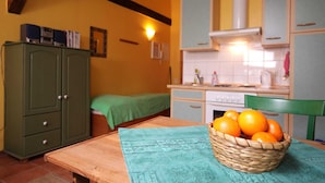 A small kitchen with a wooden table, a green cabinet, and a basket of oranges. - Apartment 2 - The Mouse - Vacation at Duckwitz Castle (Behren-Lübchin)