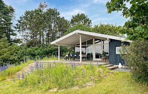 A modern house with a covered patio, surrounded by lush greenery and flowering plants. - Beautiful home in Knebel with WiFi (Knebel)