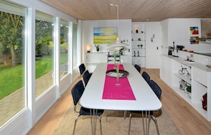 A modern dining area with a white table, black chairs, and a pink runner. There is a painting on the wall, a lamp, and shelves with various items. - Beautiful home in Knebel with WiFi (Knebel)