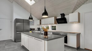 Cozinha moderna com ilha central, eletrodomésticos de aço inoxidável e iluminação pendente.