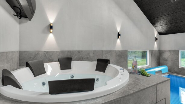 Um banheiro moderno com uma banheira de pedestal, uma janela e vista para uma piscina.