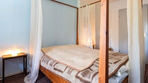 Un lit à baldaquin avec des poteaux aux quatre coins, une table de chevet et une lampe.
