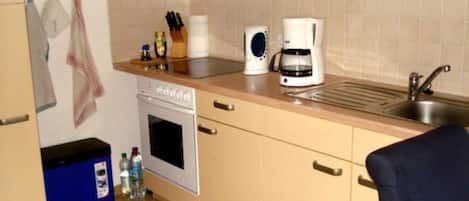 Une cuisine équipée d’une cuisinière, d’un four, d’une machine à café et d’un évier.