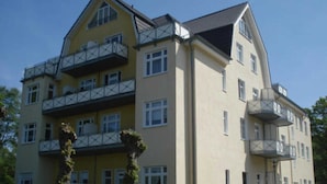 A multi-story building with balconies, a flat roof, and a symmetrical facade.