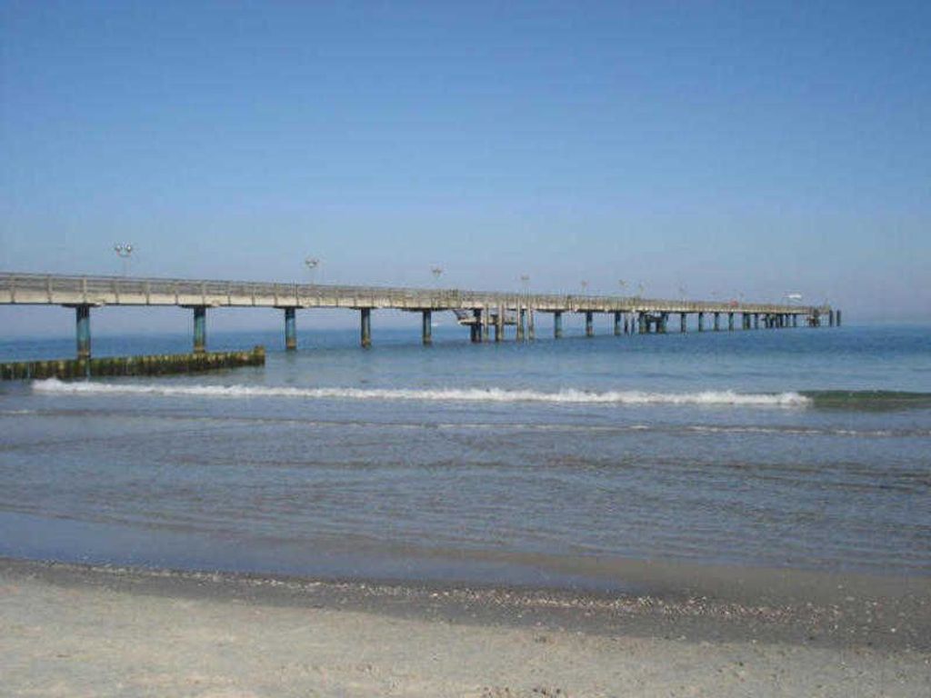 A long pier extending into the water with a clear sky above.