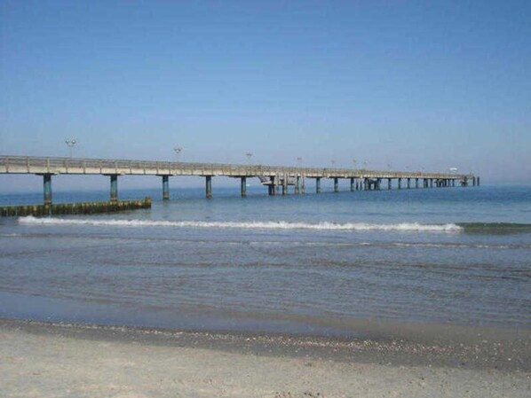 A long pier extending into the water with a clear sky above.