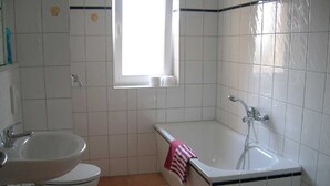 A bathroom with a sink, toilet, and bathtub. - Amber (1st floor left) - Villa Meeresrauschen (Zempin)