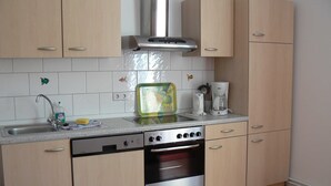 A kitchen with light wooden cabinets, a stainless steel dishwasher, an oven, a coffee maker, and a toaster. - Amber (1st floor left) - Villa Meeresrauschen (Zempin)
