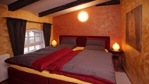 Un dormitorio con una cama grande, dos lámparas de noche, una ventana con cortinas y un cuadro en la pared.