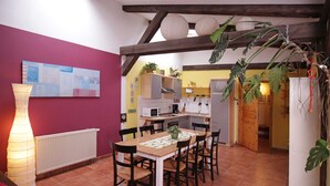 Un comedor con una mesa y sillas, una cocina al fondo y una planta en maceta.