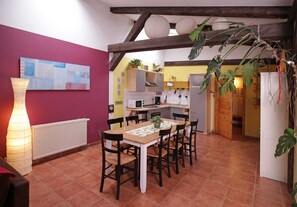 Un coin repas avec une table et des chaises, une cuisine en arrière-plan et une plante en pot.