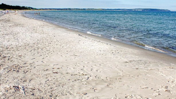 A sandy beach with footprints, calm water, and a distant shoreline. - Cozy home in Ebeltoft with sauna (Ebeltoft)