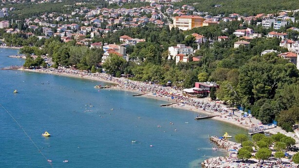A coastal town with a beach, buildings, and a clear view of the sea.
