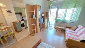 A compact living space with a kitchenette, a bed, a sofa, and a dining area.