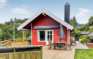 A red cabin with a deck, a chimney, and a table with chairs. - Stunning home in Farsund with ethernet internet (Farsund)