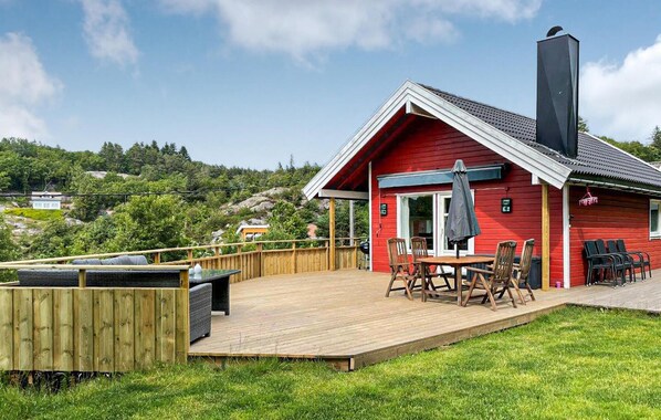 A red cabin with a deck, outdoor seating, and a chimney. - Stunning home in Farsund with ethernet internet (Farsund)