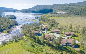 A lakeside property with multiple houses, a river, and forested hills.