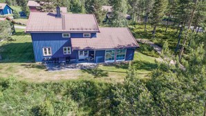 Een ruime, twee verdiepingen tellende woning met een rode dakbedekking, omgeven door een dicht bos.