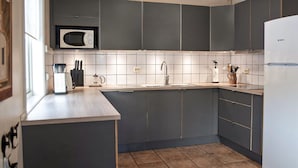 Een moderne keuken met grijze kastjes, een wit aanrecht, een ingebouwde magnetron, een spoelbak en een Bosch koelkast.