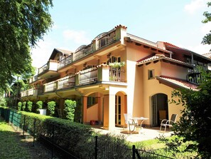 Un edificio de varios pisos con balcones, mobiliario exterior y un jardín.