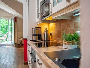 A modern kitchen with a built-in oven, a coffee maker, and a microwave. There is a potted plant on the counter.