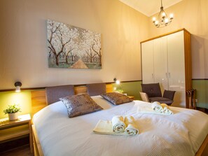 Habitación de hotel con una cama grande, dos mesitas de noche con lámparas, un armario y un cuadro en la pared.
