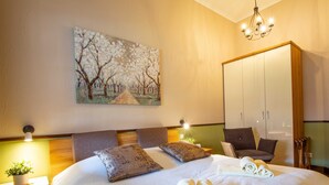 Habitación de hotel con una cama grande, dos mesitas de noche con lámparas, un armario y un cuadro en la pared.