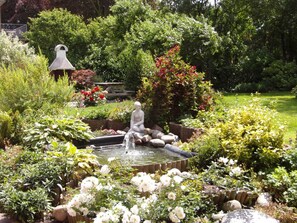 A garden with a fountain, a statue, and various plants.