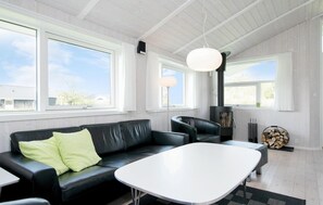 A modern living room with a black leather sofa, a white coffee table, and a wood-burning stove. - Lovely home in Hadsund with sauna (Hadsund)