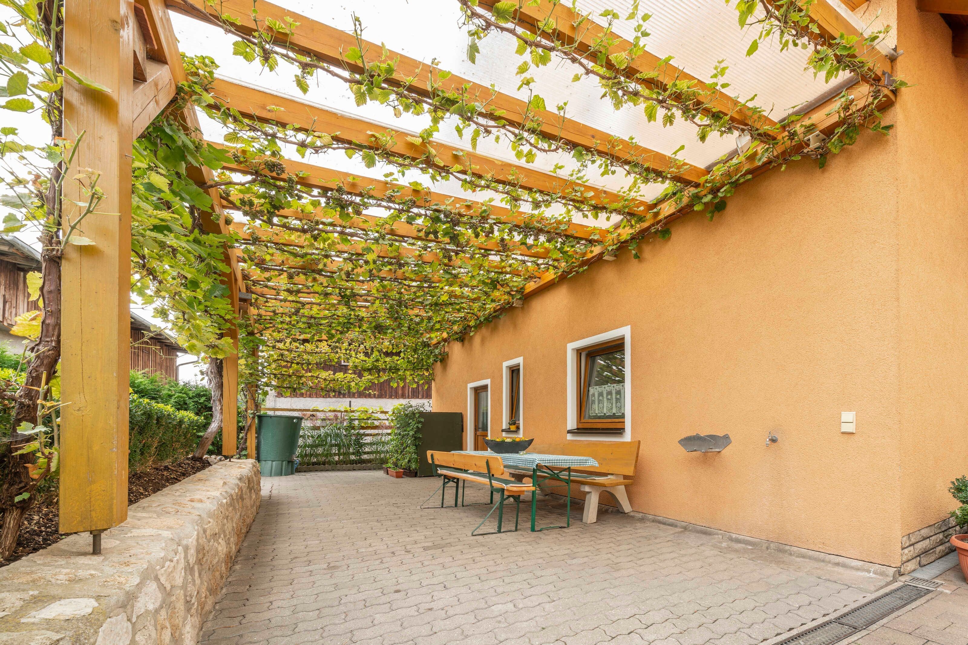 A covered patio with a wooden pergola, a table, and chairs.