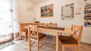 A dining area with a wooden table and chairs, a painting on the wall, and a bulletin board with various papers. - Dormitory Room - Small Room (Heiligenstadt i.OFr.)