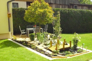 A well-maintained garden with a wooden deck, chairs, and a table. - Dormitory Room - Small Room (Heiligenstadt i.OFr.)