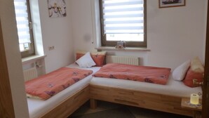 A small, cozy room with two wooden beds, a radiator, and a window with blinds. - Dormitory Room - Small Room (Heiligenstadt i.OFr.)