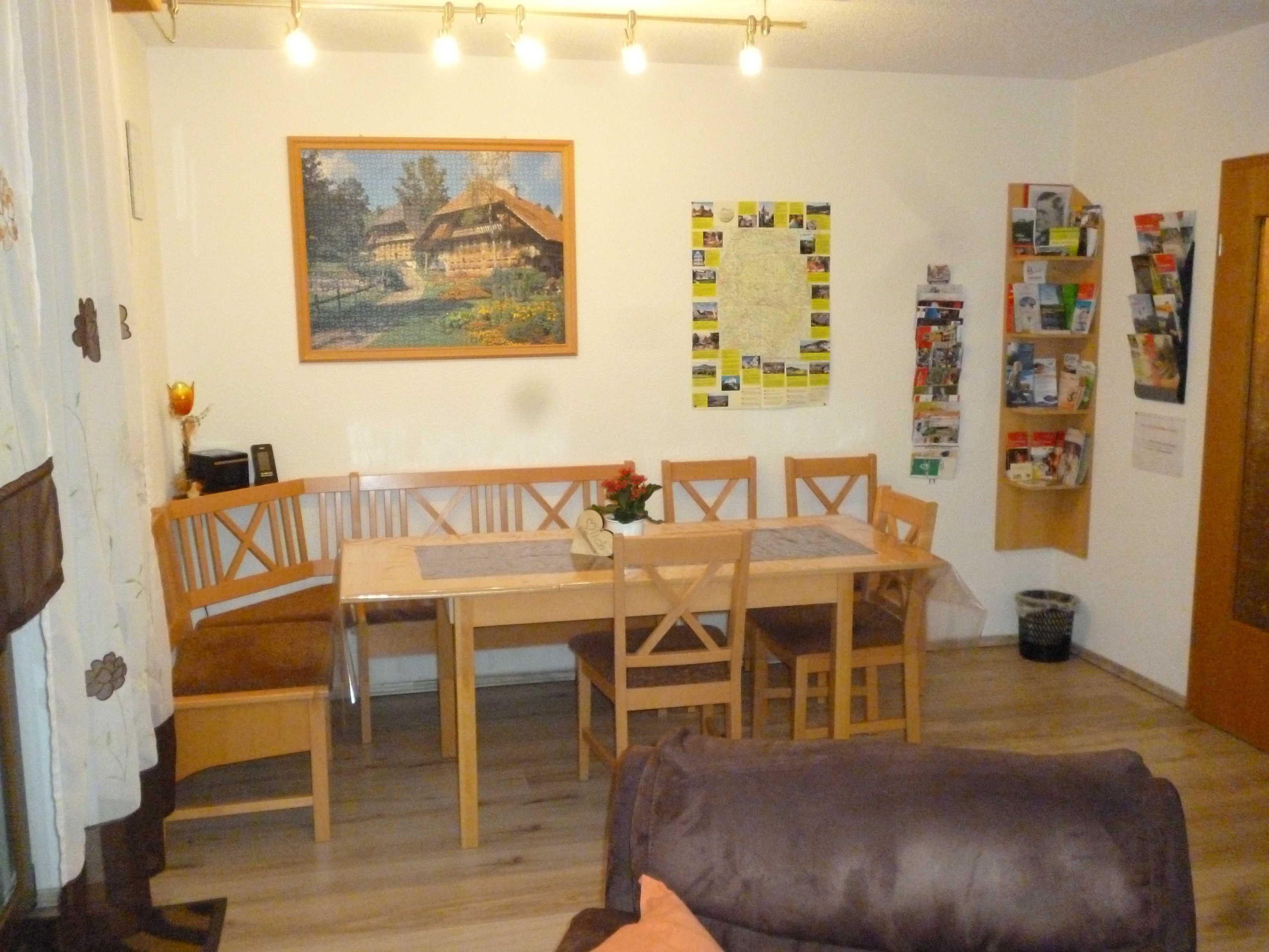 En hyggelig stue med et træbord, bænke og en brun lædersofa.