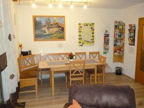 A cozy living room with a wooden dining table, benches, and a brown leather sofa. - Dormitory Room - Small Room (Heiligenstadt i.OFr.)