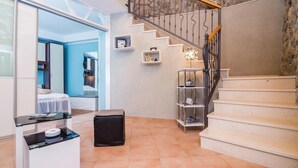 Un interior moderno con una escalera, un escritorio pequeño y una zona de estar con una pared azul.