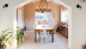 A dining area with a wooden table and chairs, a chandelier, and a view of the outdoors through a window. - Amazing home in Rochefort (Rochefort)