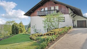 Een twee verdiepingen tellend huis met een balkon, een garage en een verzorgde tuin.
