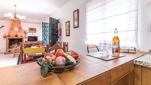 A dining area with a table set for two, a fruit basket, and a bottle of liquor on the counter. - Amazing home in Torrox Costa with WiFi (Torrox Costa)
