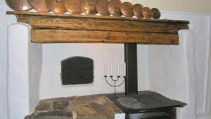 Ein Steinkamin mit hölzernem Sims, auf dem mehrere Kupferkessel stehen.