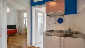 Een moderne keuken met een ingebouwde kookplaat, witte kasten en een blauwe spatwand.