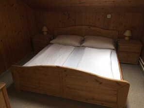 A wooden bed with two nightstands, each with a lamp.