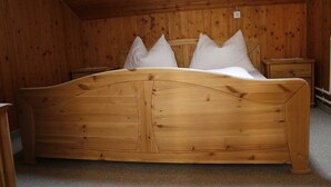 Un letto di legno con testiera, due comodini e cuscini bianchi in una stanza con pareti e soffitto in legno.